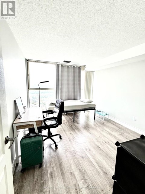 A room with a desk, chair, and a bed with a window.