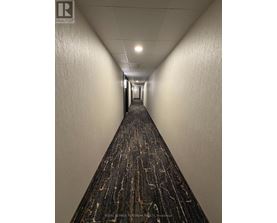 A long hallway with a carpeted floor and white walls.