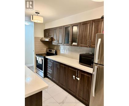 A kitchen with wooden cabinets and a stainless steel refrigerator.