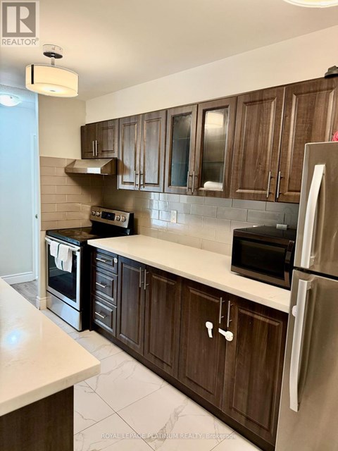 A kitchen with wooden cabinets and a stainless steel refrigerator.
