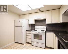 A kitchen with white appliances and black countertops.