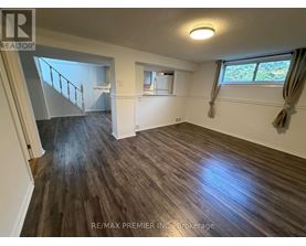 A room with wooden flooring and a window with curtains.