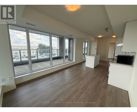 A spacious room with wooden floors and large windows overlooking a cityscape.