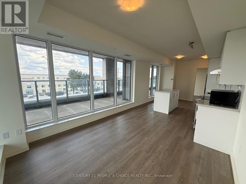 A spacious room with wooden floors and large windows overlooking a cityscape.