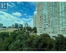 A view of a cityscape with a large building in the foreground and a clear blue sky above.