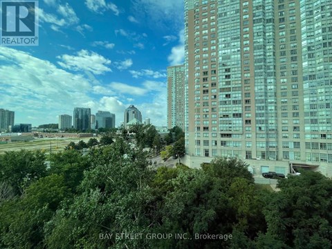 A view of a cityscape with a large building in the foreground and a clear blue sky above.