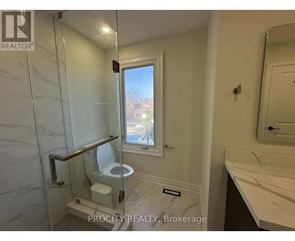 A bathroom with a toilet, sink, and window.