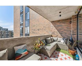 A balcony with a couch, pillows, and plants.