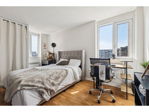 A bedroom with a bed, desk, and chair.