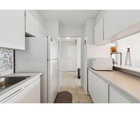 A kitchen with white cabinets and a white refrigerator.