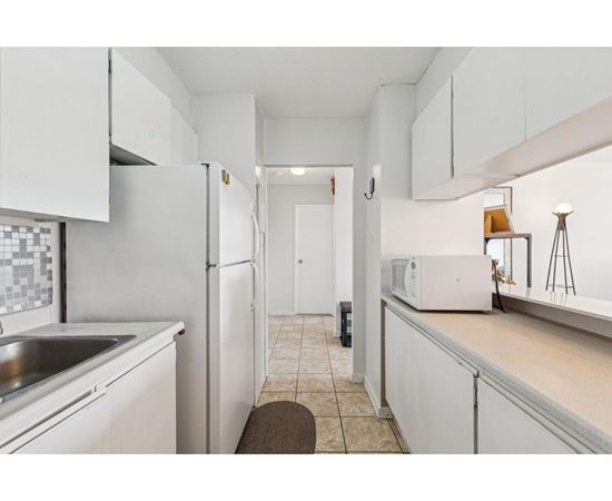 A kitchen with white cabinets and a white refrigerator.