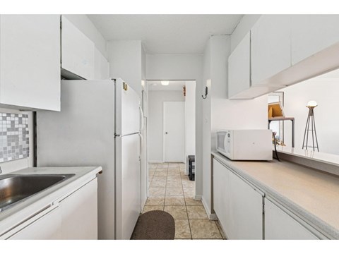 A kitchen with white cabinets and a white refrigerator.