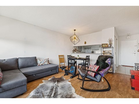 A grey couch sits in a living room with a black rocking chair.