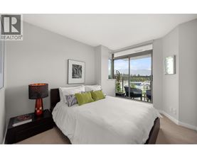 A bedroom with a large bed and a view of the outdoors through a sliding glass door.