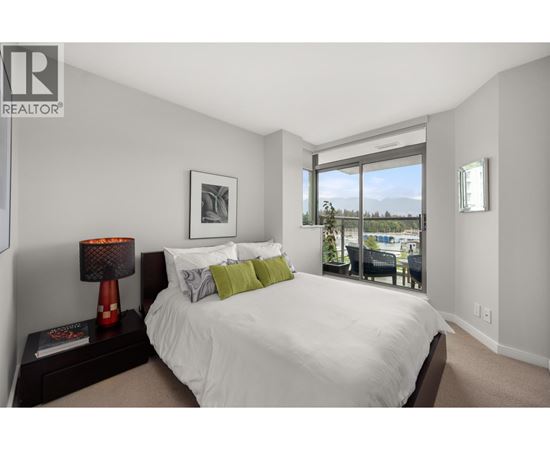 A bedroom with a large bed and a view of the outdoors through a sliding glass door.