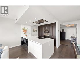 A modern kitchen with white cabinets and a wooden floor.