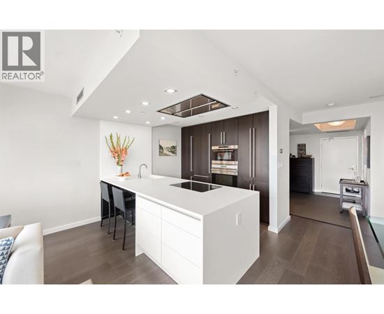 A modern kitchen with white cabinets and a wooden floor.