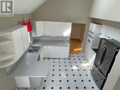 A kitchen with white cabinets and a black and white checkered floor.