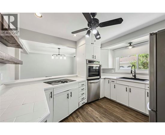 A modern kitchen with white cabinets and stainless steel appliances.