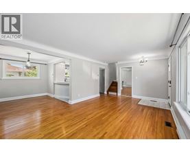 A spacious room with wooden floors and white walls.