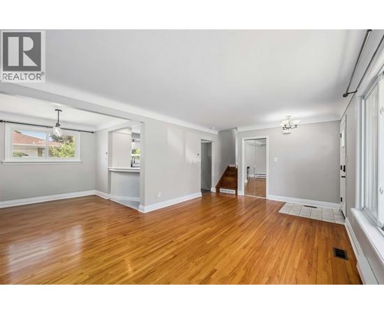 A spacious room with wooden floors and white walls.