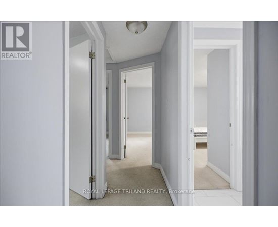 A hallway with white walls and a carpeted floor.