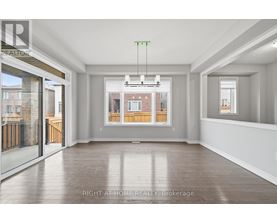 A spacious room with a view of a brick building through the window.