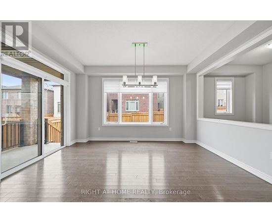 A spacious room with a view of a brick building through the window.
