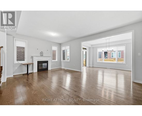 A spacious living room with wood flooring and a fireplace.