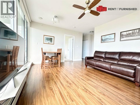 A living room with a brown leather couch and wooden floors.
