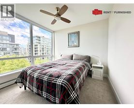 A bedroom with a large bed and a window overlooking a cityscape.