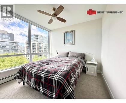 A bedroom with a large bed and a window overlooking a cityscape.