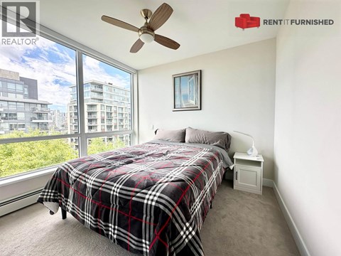 A bedroom with a large bed and a window overlooking a cityscape.