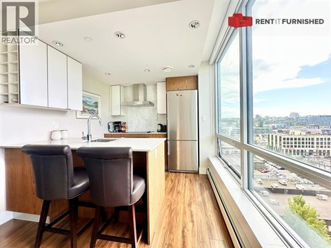A kitchen with brown chairs and a view of the city.