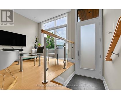 A living room with a television, a glass table, a sofa, and a staircase.