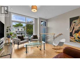 A living room with a glass table and chairs, a television, and a painting on the wall.