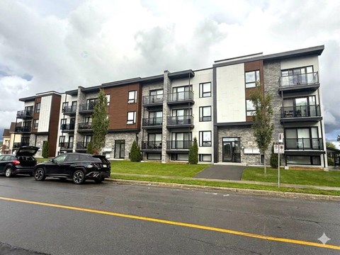 A black SUV is parked in front of a multi-story apartment building.