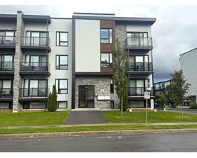 A modern apartment building with balconies and a no parking sign.