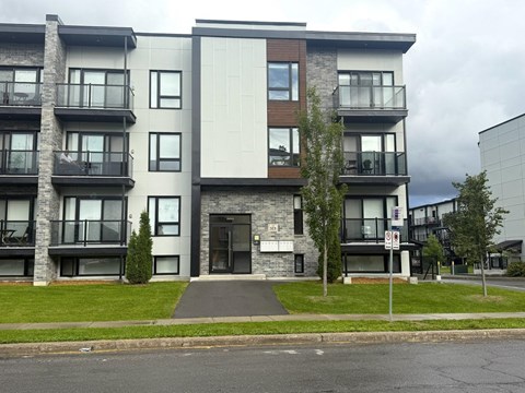 A modern apartment building with balconies and a no parking sign.