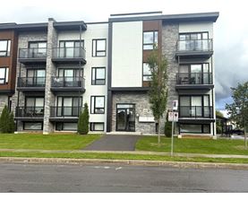 A modern apartment building with a white facade and black balconies.