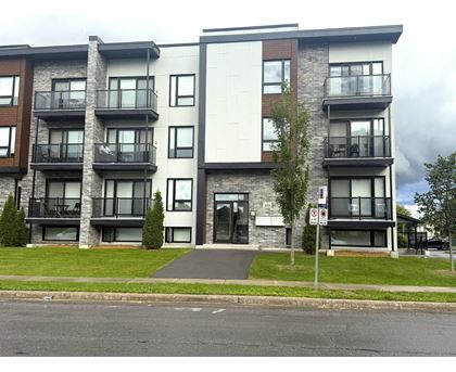 A modern apartment building with a white facade and black balconies.