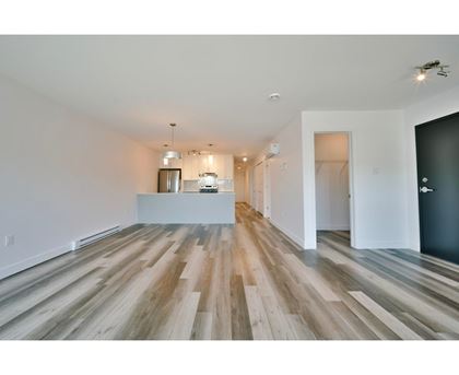 A long, empty room with wooden floors and white walls.