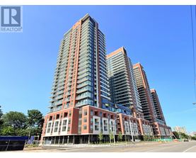 A tall residential building with a red and grey facade stands under a clear blue sky.
