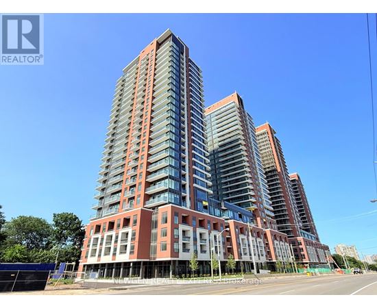 A tall residential building with a red and grey facade stands under a clear blue sky.