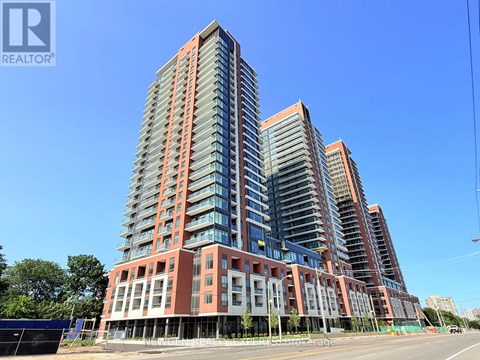A tall residential building with a red and grey facade stands under a clear blue sky.