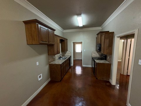 A kitchen with brown cabinets and a brown floor.