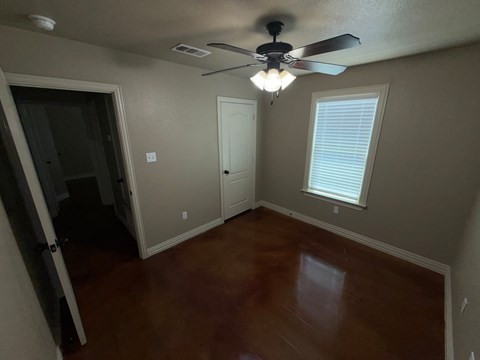 A room with a ceiling fan and a window with blinds.