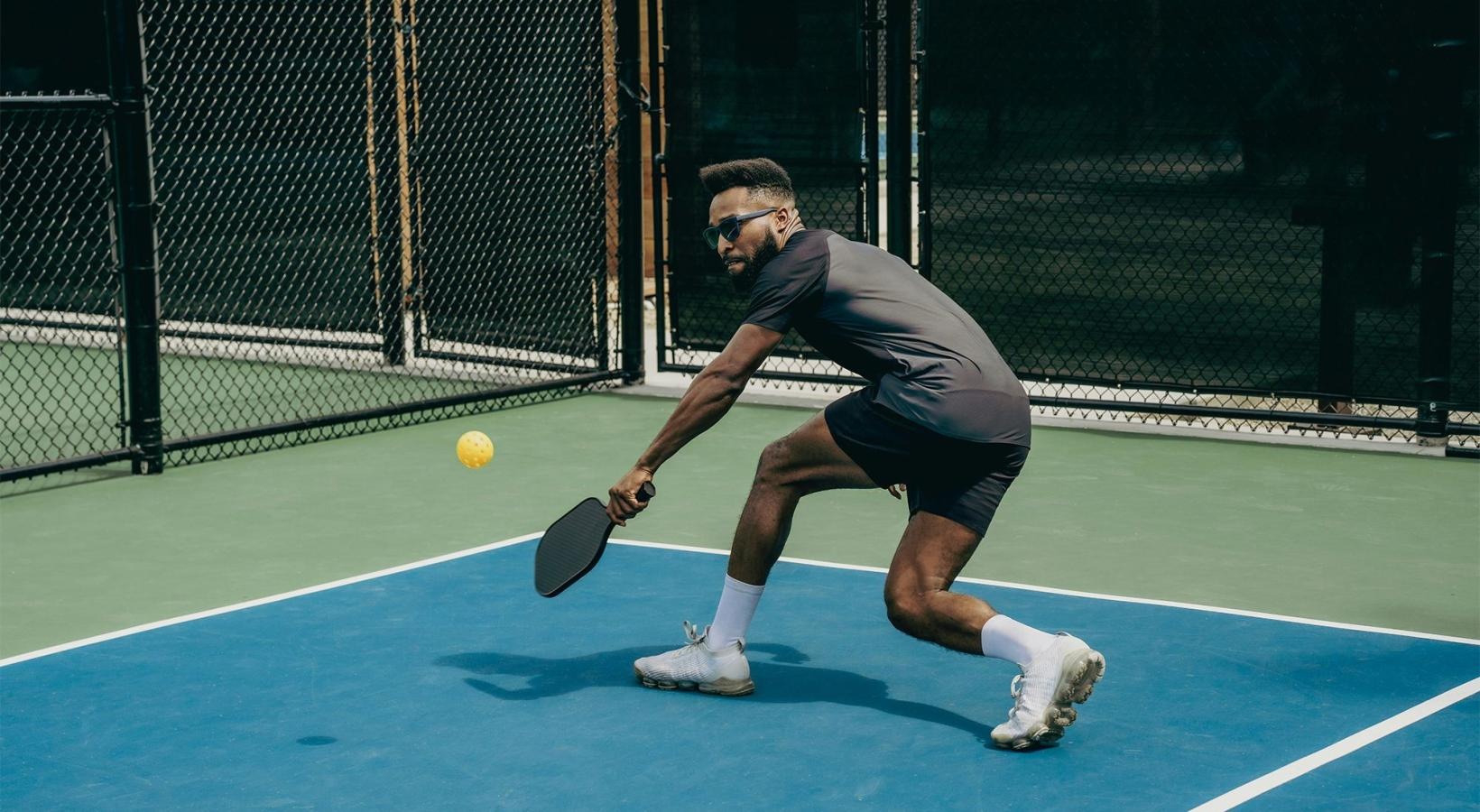 A man playing tennis on a blue court.