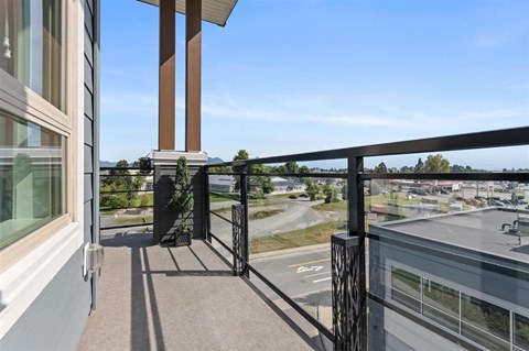 A balcony with a view of a parking lot and trees.