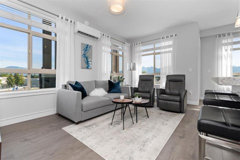 A living room with a grey couch, a black leather chair, and a white rug.